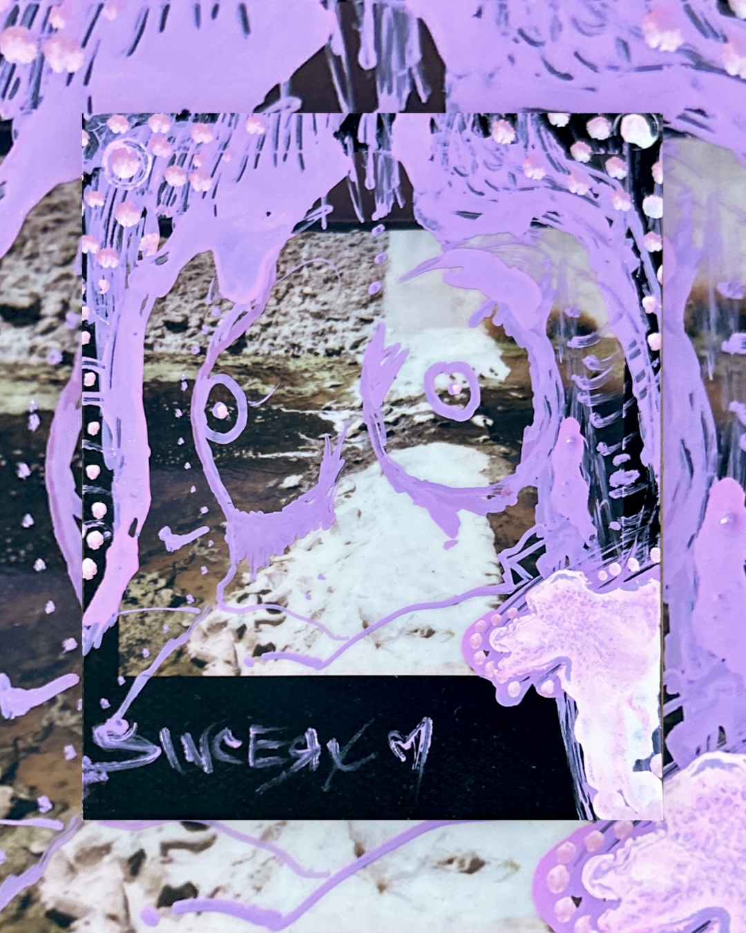 a lilac face painted over a Polaroid of a rocky creek