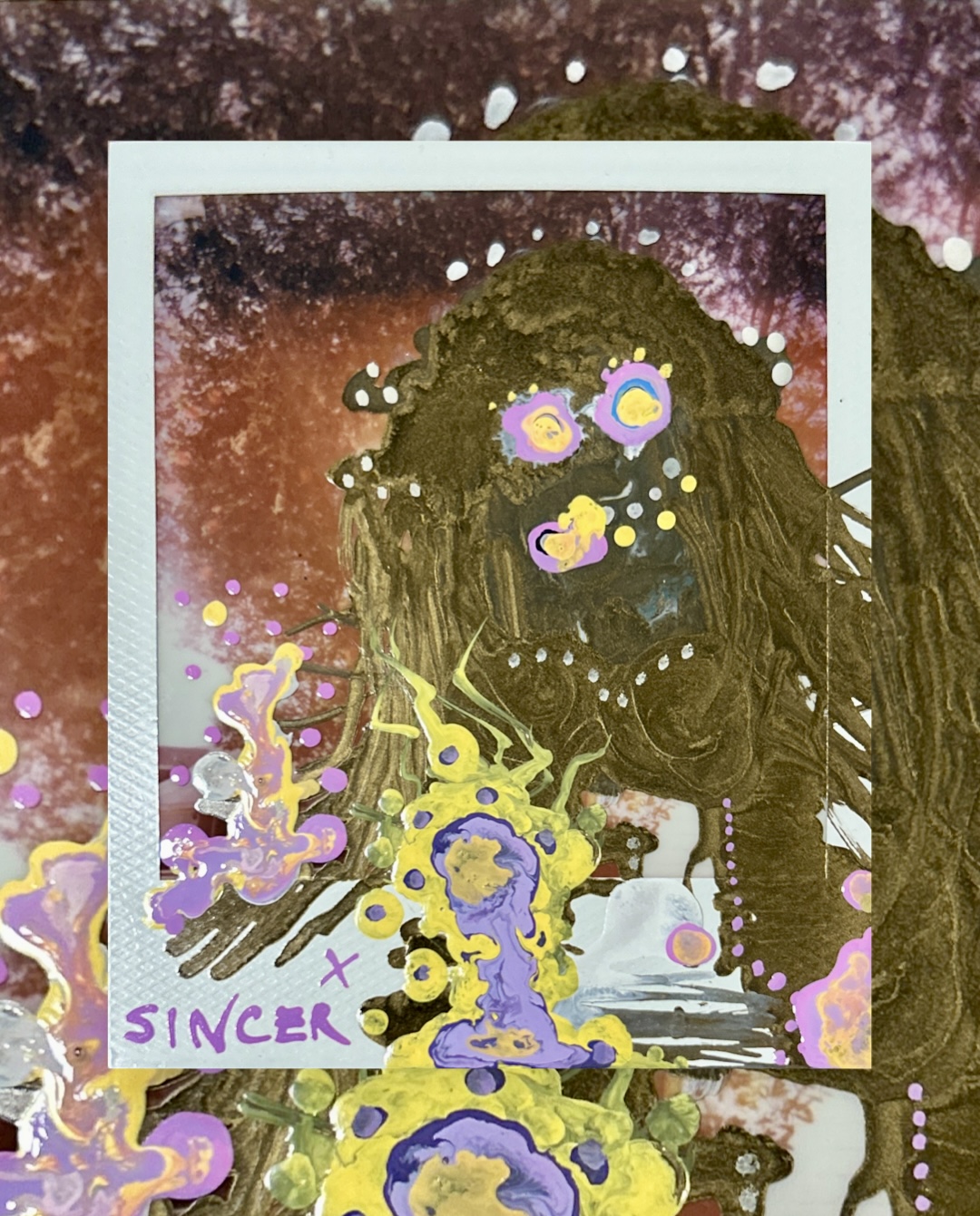 a gold-toned figure with wild hair painted over a Polaroid, purple and yellow accents