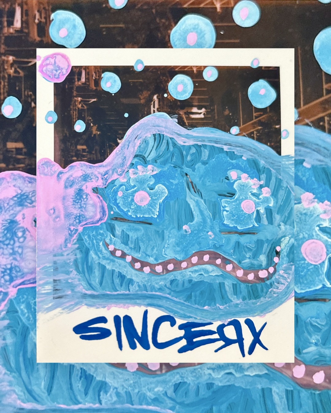 a wide-eyed grinning creature in light blue and pink paint surrounded by dotted spheres, signed across the border