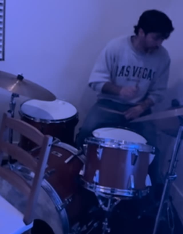 Alberto playing a drum kit in a blue-lit room